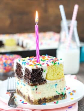 slice of ultimate birthday cake on white plate with pink candle on top