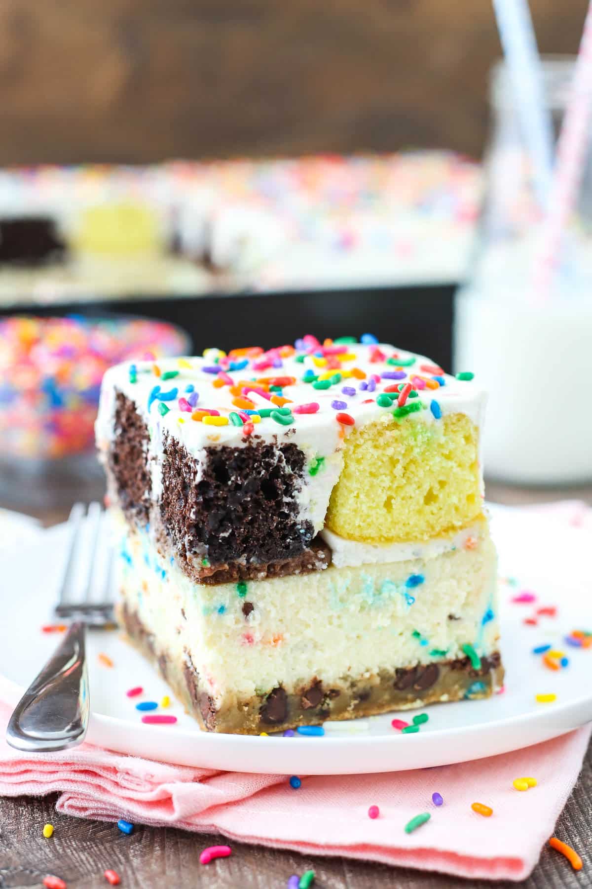 slice of ultimate birthday cake on white plate and pink napkin