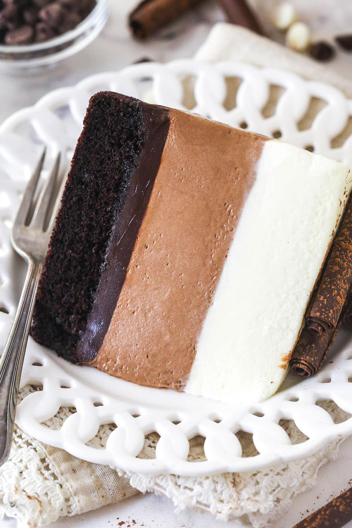 A slice of triple chocolate mousse cake on a white plate with a fork
