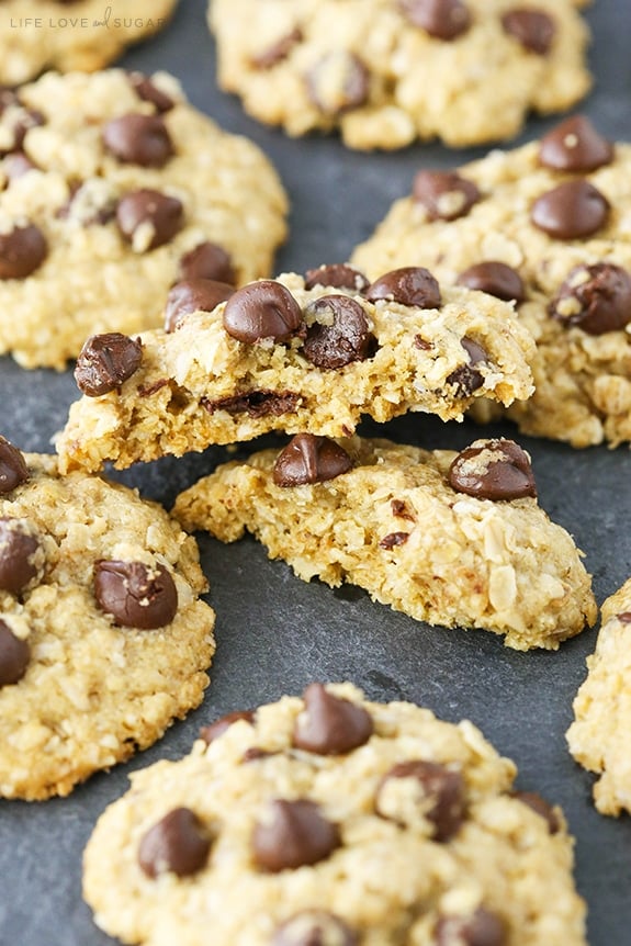 Oatmeal Chocolate Chip Cookies on a dark surface with one cookie broken in half