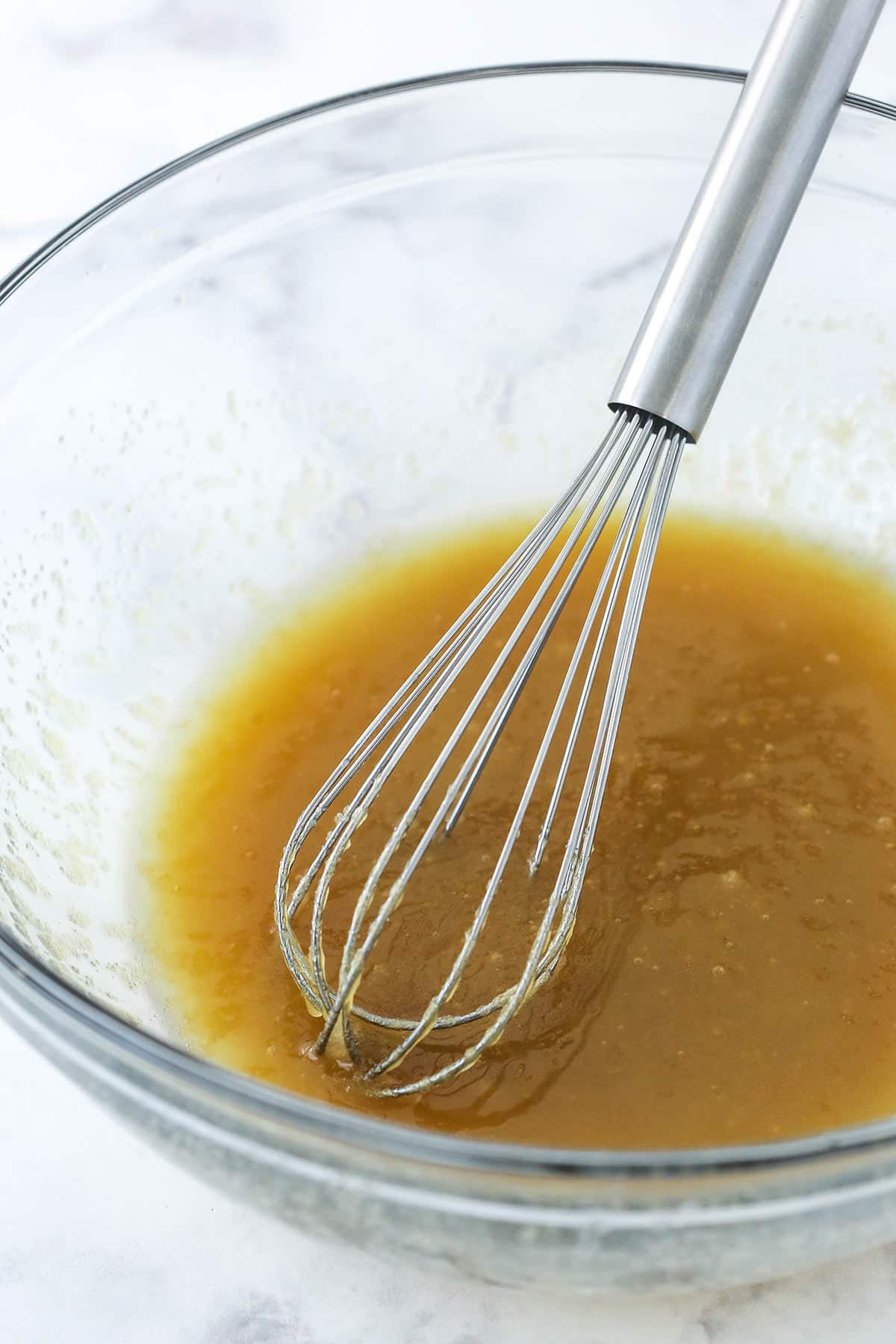 Butter, brown sugar, and sugar mixed together in glass bowl.