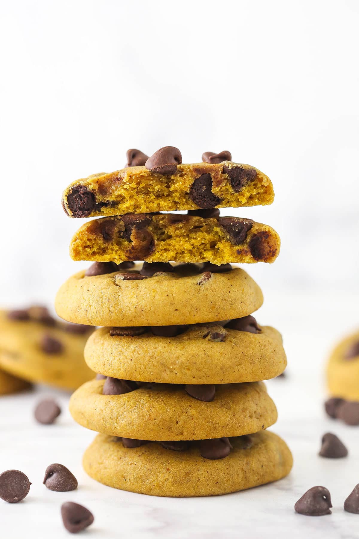 stack of 4 pumpkin chocolate chip cookies with a broken cookie on top