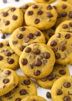 A scattered pile of pumpkin chocolate chip cookies on marble countertop.