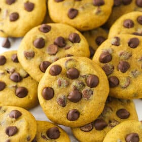 A scattered pile of pumpkin chocolate chip cookies on marble countertop.