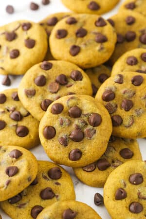 a scattered pile of pumpkin chocolate chip cookies on marble countertop