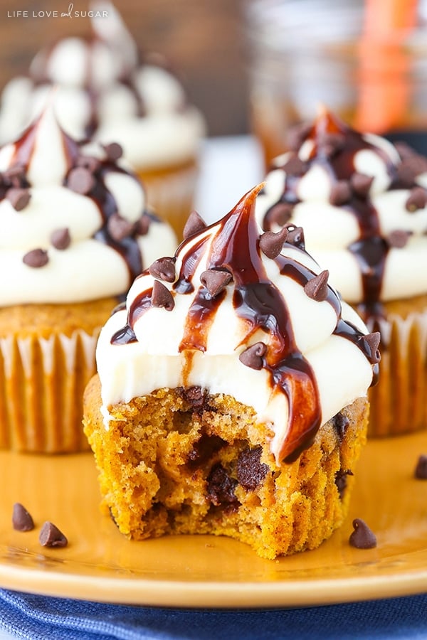 A pumpkin spice cupcake with chocolate chips and cream cheese frosting with a bite missing