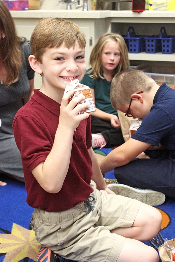 A Kid Drinking Milk Through a Straw and Smiling