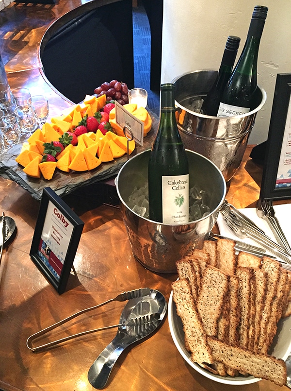 A Wooden Table Displaying Chilled Wine, Crackers, Cheese and Fruit