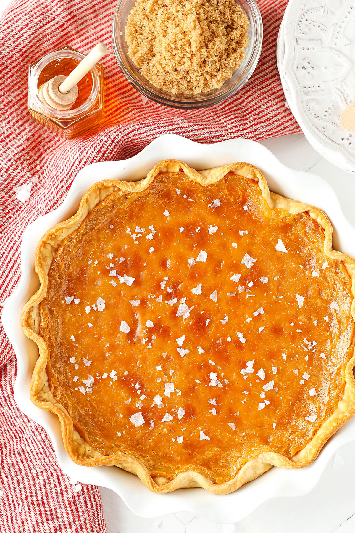 An overhead shot of a salted honey pie on a countertop beside a cloth napkin