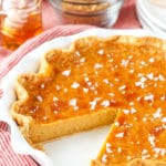 A homemade honey pie in a white pie plate with one slice missing