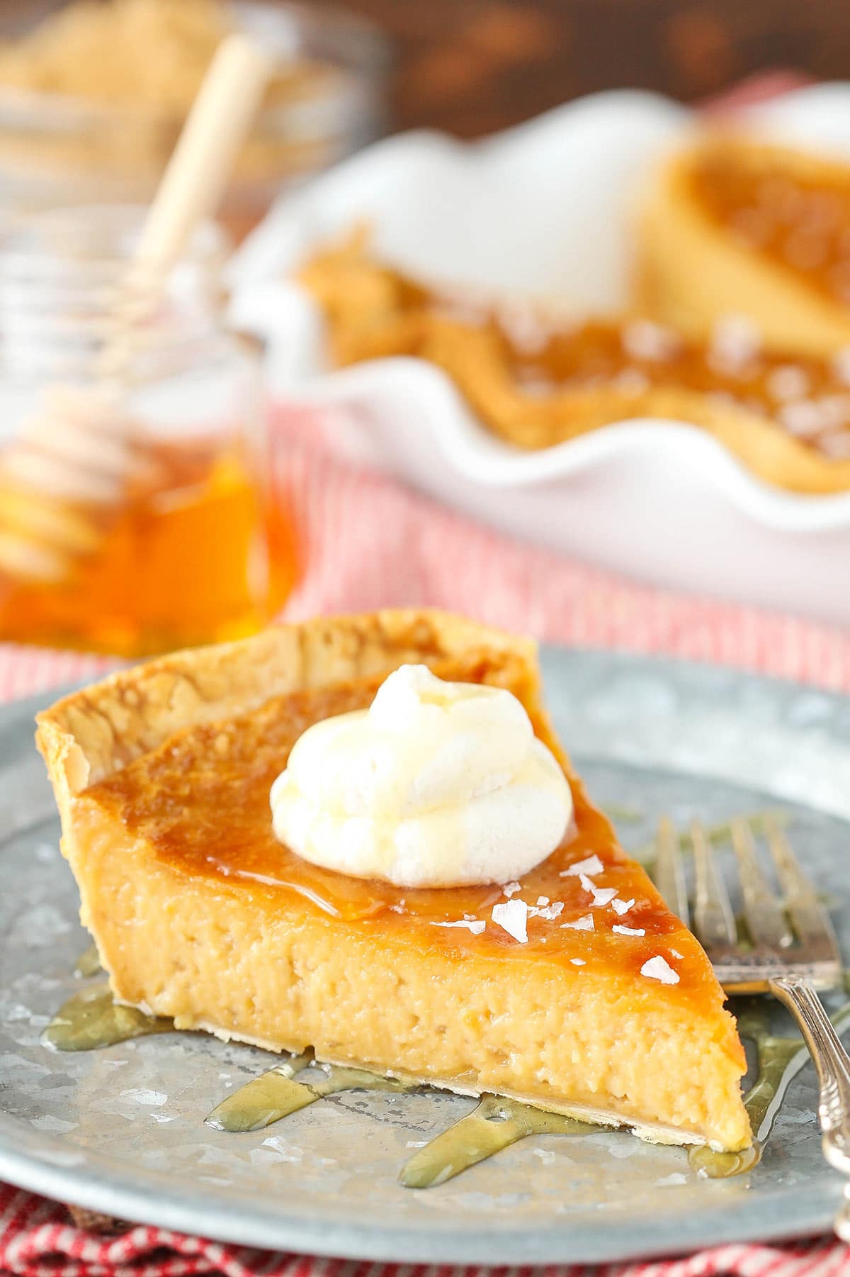 A slice of salted honey pie on a metal serving platter beside a large fork