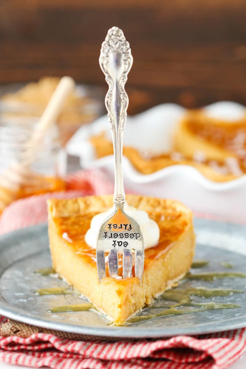 A piece of pie on a plate with a fork that says "eat dessert first" poking into it