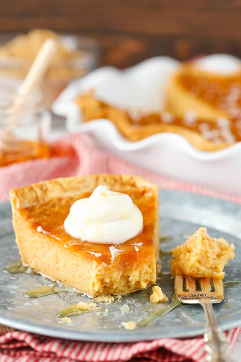 A slice of honey pie on a round metal platter with one bite on a fork