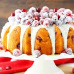 A cranberry bundt cake with white chocolate ganache on top of a cake stand