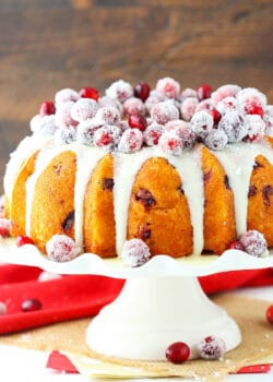 A cranberry bundt cake with white chocolate ganache on top of a cake stand
