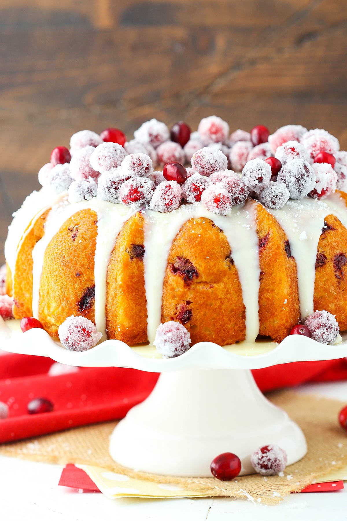 A cranberry bundt cake with white chocolate ganache on top of a cake stand