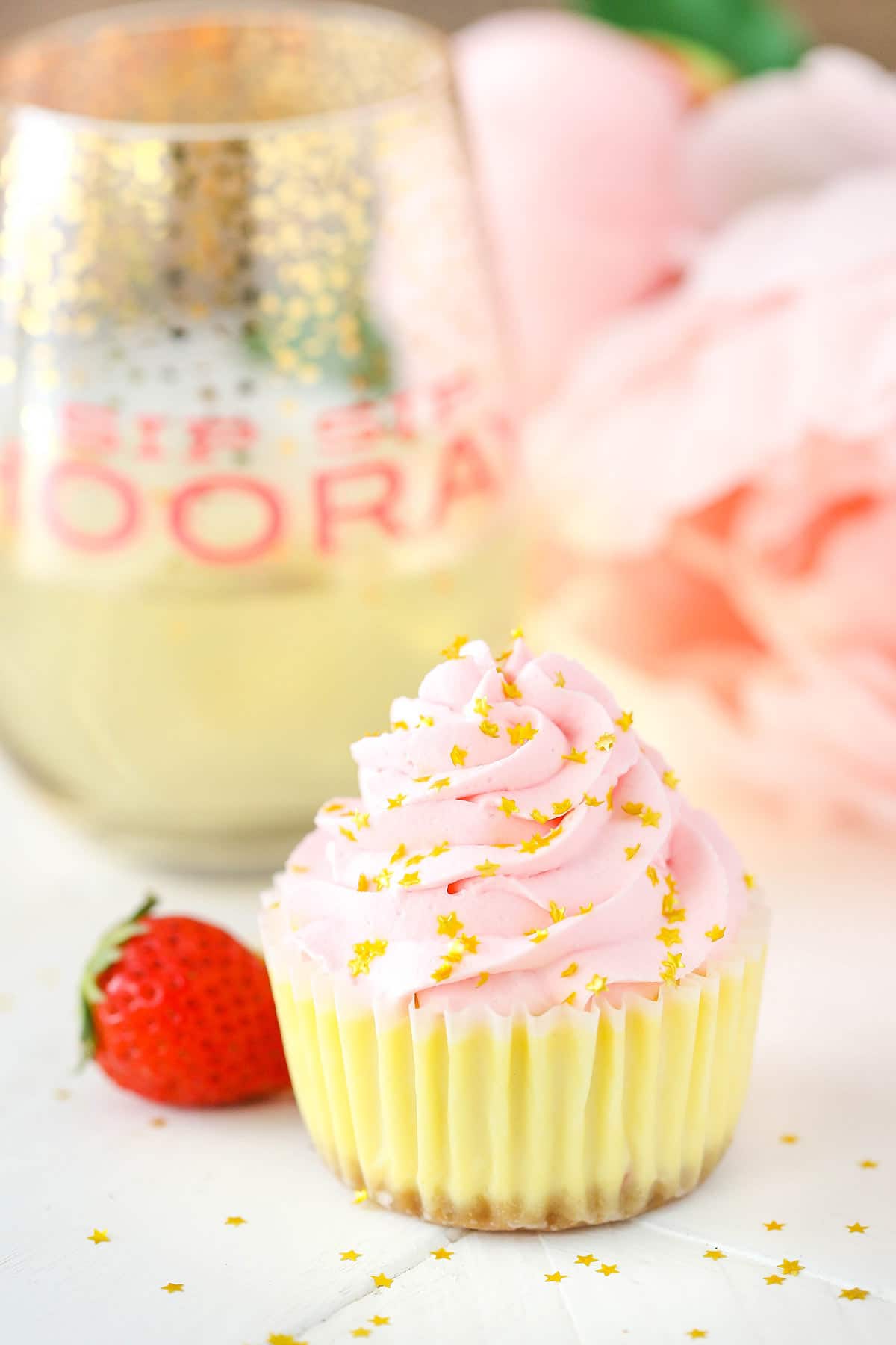 A mini cheesecake on a countertop with a glass of champagne in the background