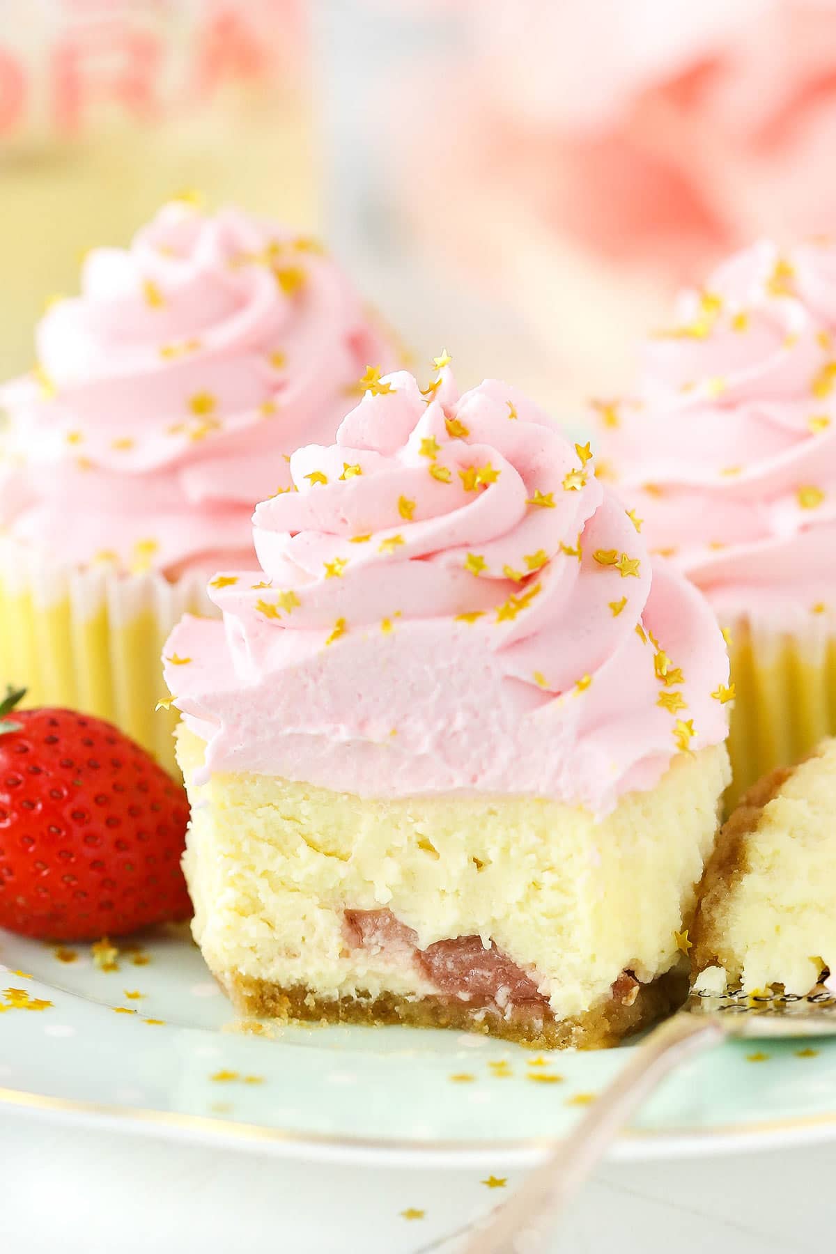 A mini strawberry champagne cheesecake with a bite taken out to reveal the strawberry chunks inside