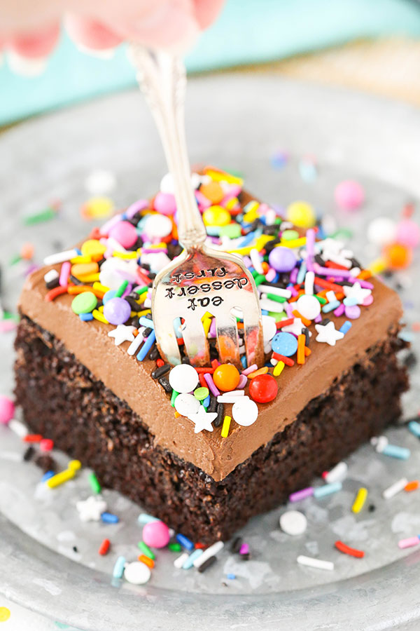 A fork taking a bit out of a slice of chocolate sheet cake.