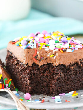 A slice of chocolate sheet cake on a plate with a bite taken out of it.