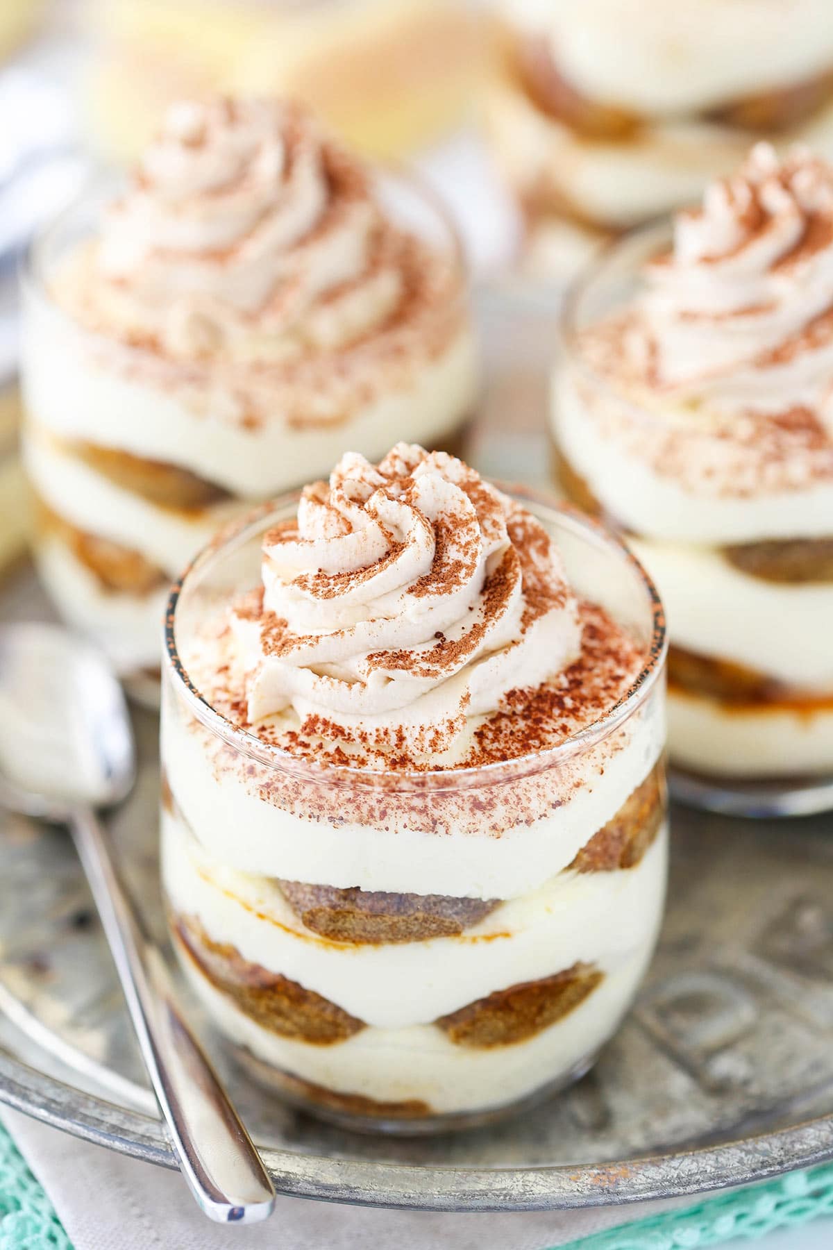 A close-up shot of a group of three tiramisu trifles on a serving platter