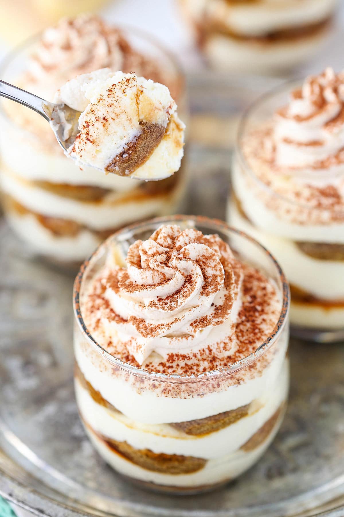 A spoonful of tiramisu hovering above a trifle topped with Kahlua whipped cream and cocoa powder