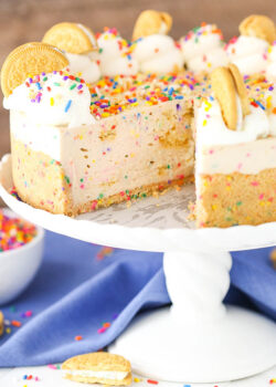 Easy no-bake Funfetti oreo birthday cake cheesecake on a cake stand with a slice taken out of it.