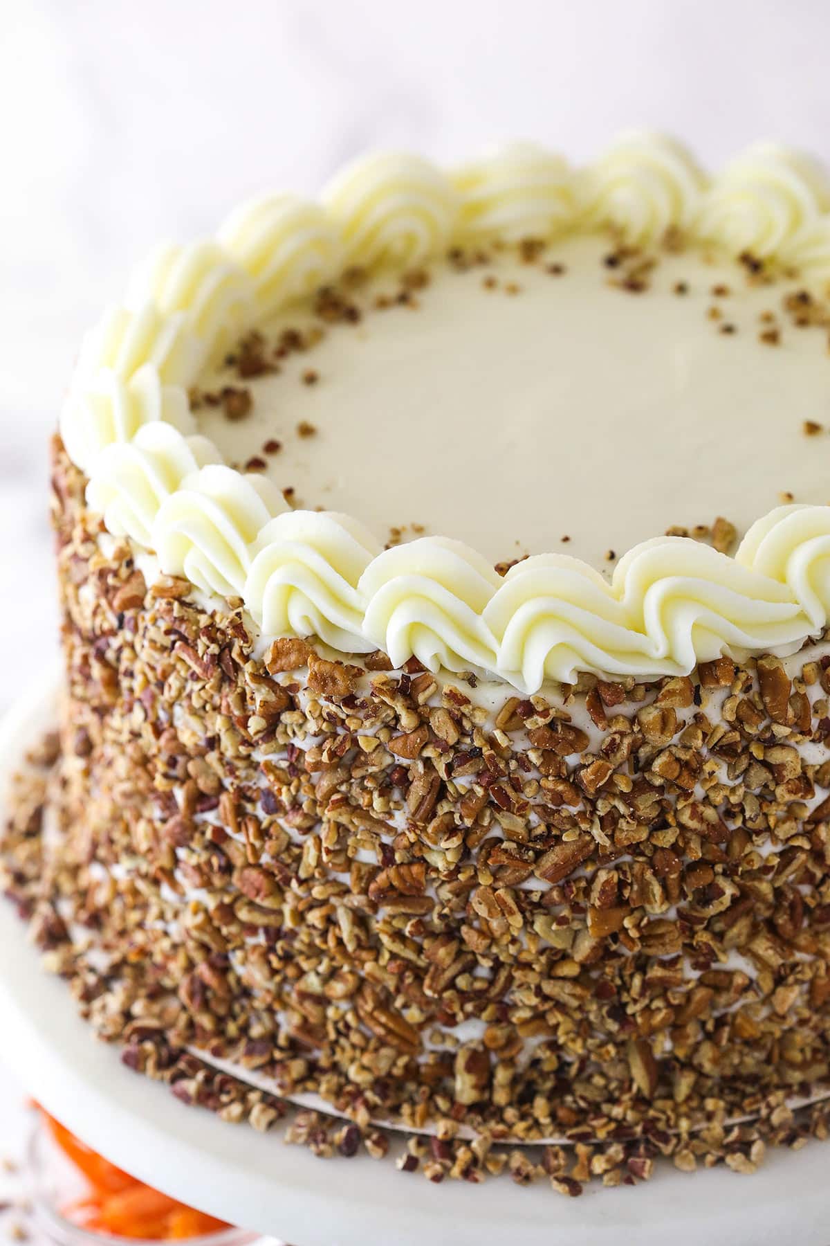 close up of full carrot cake cheesecake cake on cake stand
