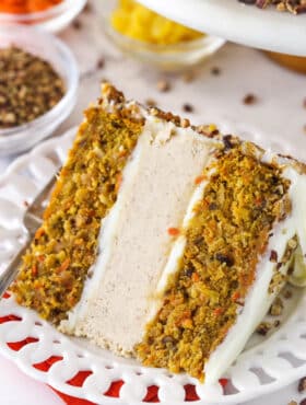 slice of carrot cake cheesecake cake on white plate with pecans, pineapple and carrots in bowls in the background