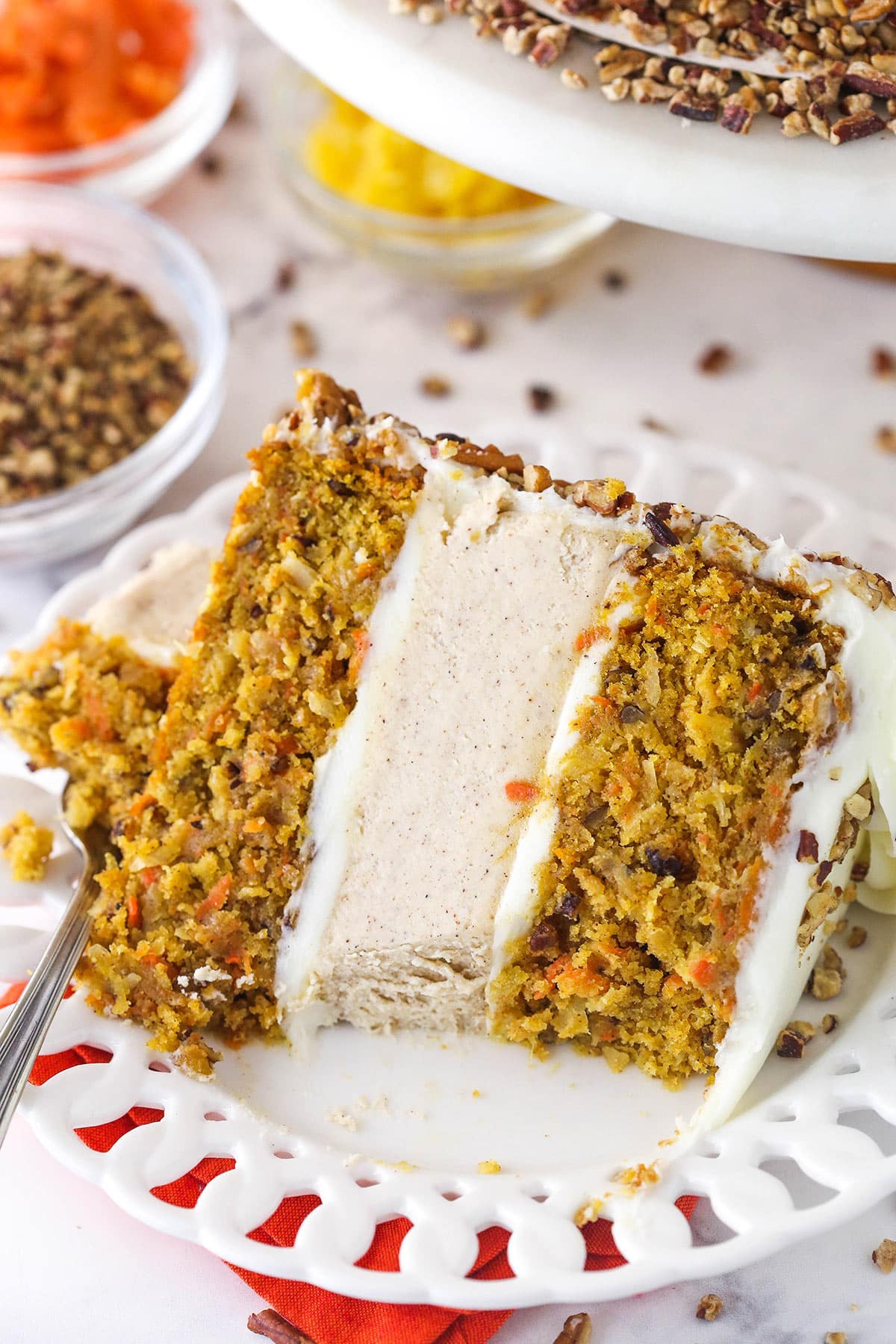 slice of carrot cake cheesecake cake on white plate with a bite taken