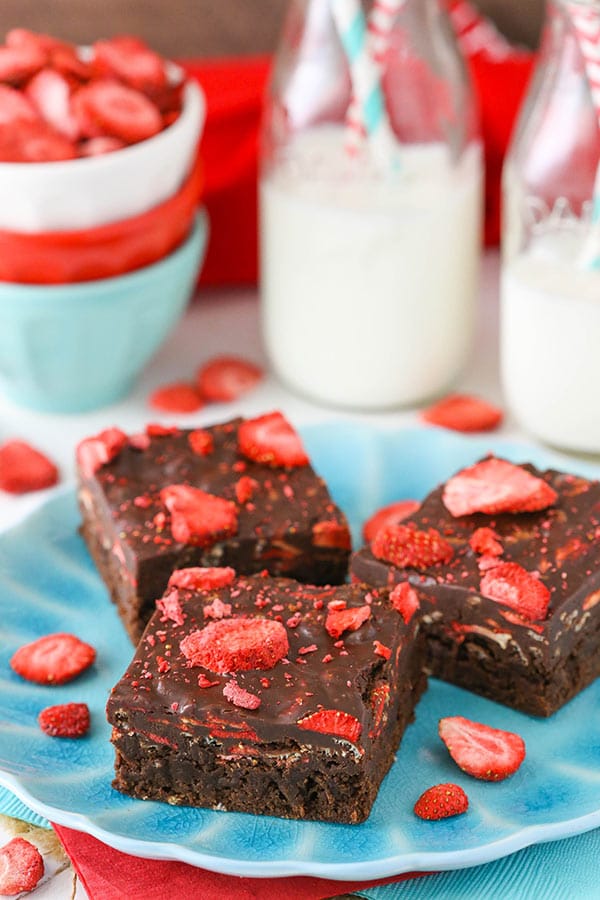 3 Strawberry Chocolate Brownies on a blue plate with milk jars in back