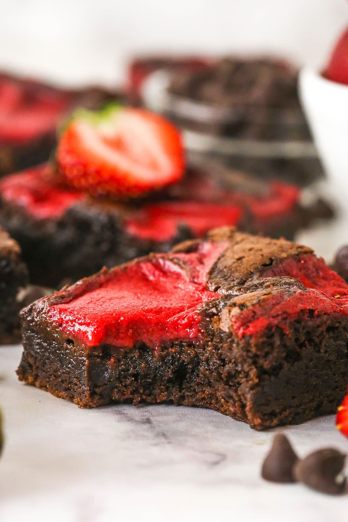 Strawberry sauce is swirled on top of moist, cakey brownies, adding a pop of color and fresh fruit flavor in these strawberry brownies. A strawberry brownie with a bite missing
