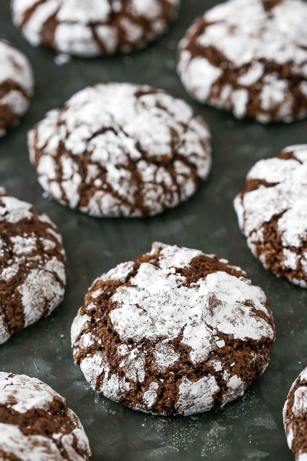 Chocolate crinkle cookies on a gray surface.
