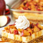 A close-up shot of a piece of caramel apple cheesecake with an apple slice and more cheesecake in the background