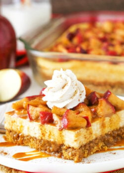 A close-up shot of a piece of caramel apple cheesecake with an apple slice and more cheesecake in the background