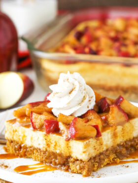 A close-up shot of a piece of caramel apple cheesecake with an apple slice and more cheesecake in the background