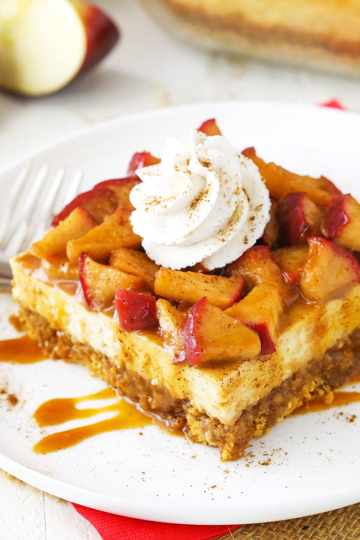 A caramel apple cheesecake bar on a white plate with caramel sauce drizzled overtop