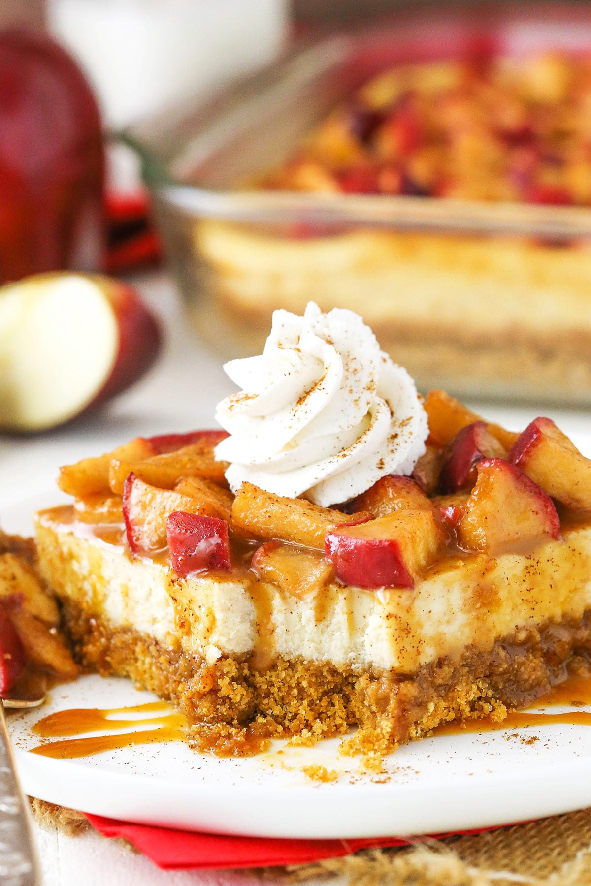 A caramel apple cheesecake bar on a plate with one bite taken out of the corner