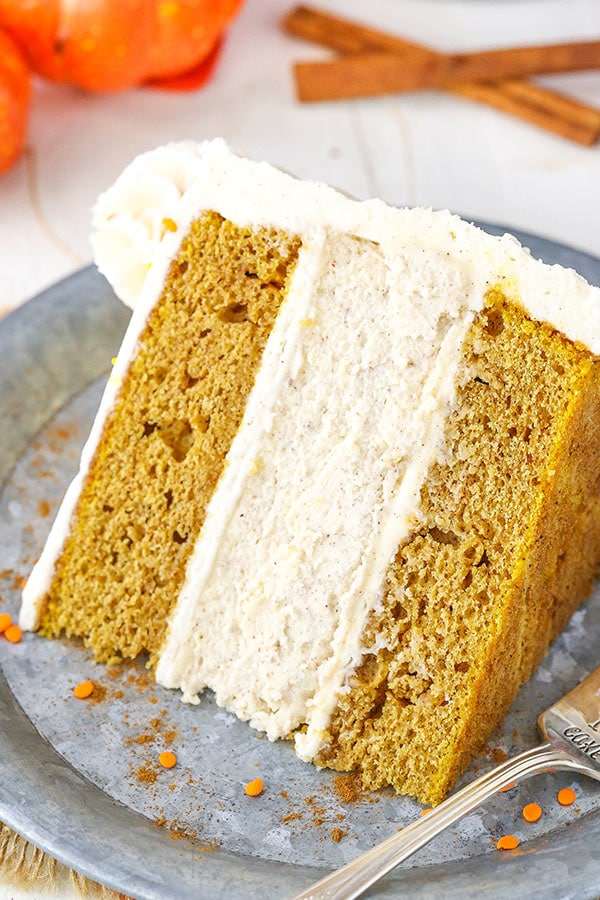 Slice of pumpkin cheesecake cake topped with cinnamon cream cheese frosting.