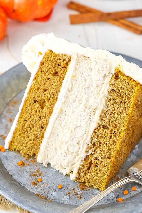 Slice of pumpkin cheesecake cake topped with cinnamon cream cheese frosting.