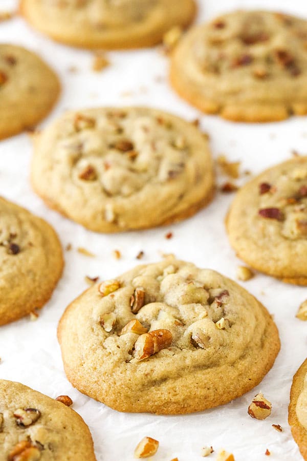 Butter Pecan Cookies laid out on white paper surrounded by more nuts