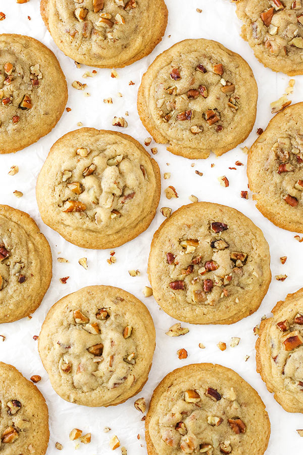 Overhead view of cookies spread out on white paper with nuts sprinkled all around 