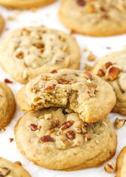 A butter pecan cookie with bite taken out stacked on more cookies.