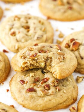 A butter pecan cookie with bite taken out stacked on more cookies.