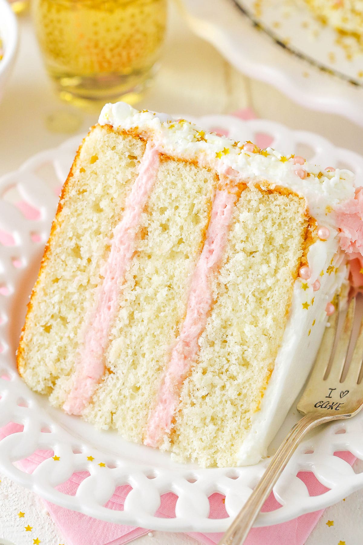 A close-up shot of a piece of strawberry champagne cake on a plate with a fork