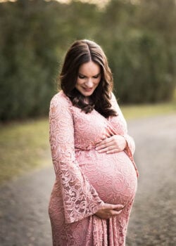 Lindsay Standing in a Pink Dress, Looking Down at her Stomach