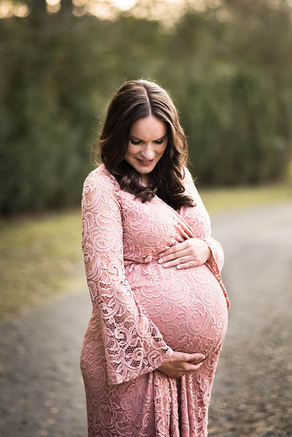 Lindsay Standing in a Pink Dress, Looking Down at her Stomach