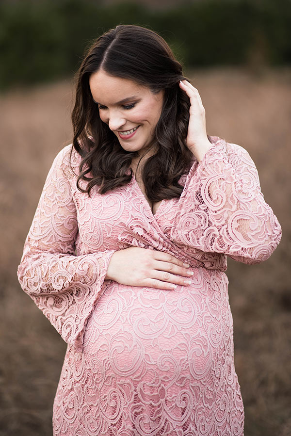 Lindsay Smiling in a Lacey Dress with a Hand on Her Baby Bump