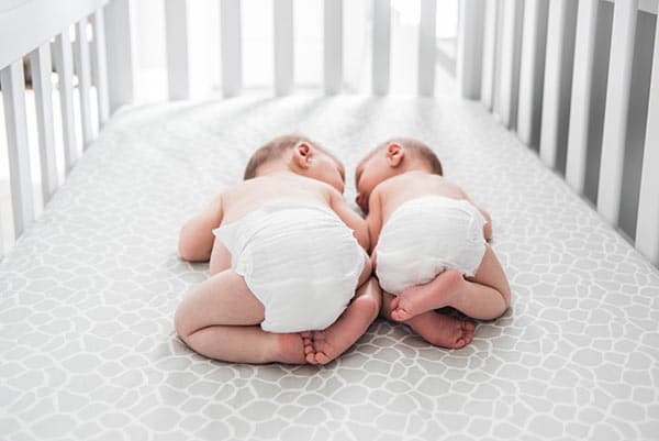 Brooks and Ashton Lying Face to Face in their Crib