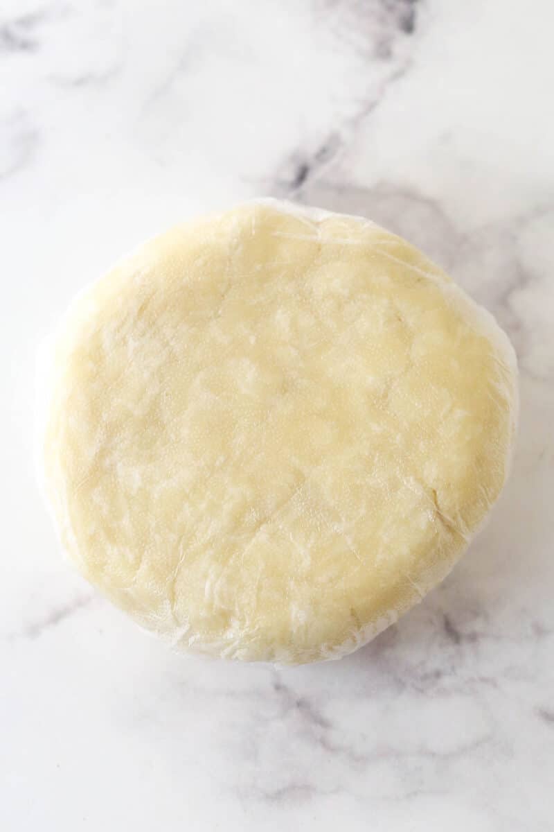 This coconut cream pie is a classic, creamy dessert made from rich coconut custard filling topped with whipped cream in a buttery pie crust. Pie dough shaped into a ball.